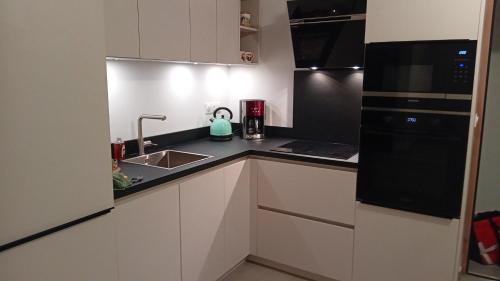 a kitchen with white cabinets and black appliances at T2 neuf situation Topissime village de Cargèse Vue mer Toutes commodités in Cargèse