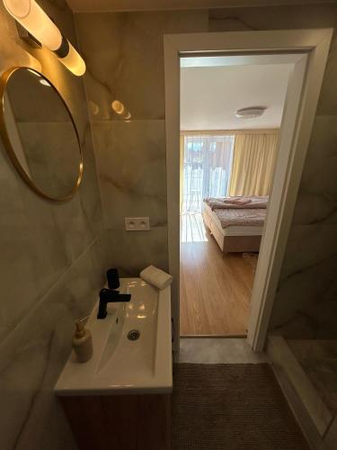 a bathroom with a sink and a mirror and a bed at Apartments ZARA-Premium Only Room in Štúrovo