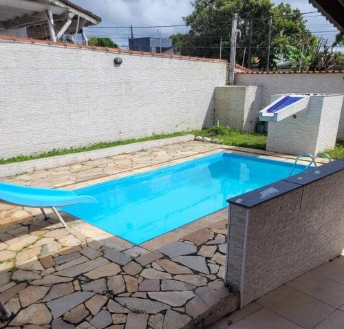 a swimming pool in a yard with a chair next to it at Casa com piscina Itanhaém in Itanhaém