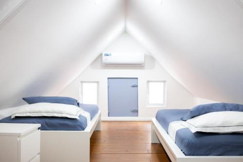 ウィレムスタッドにあるWillemstad Cityscape Staysのドア付きの白い部屋のベッド2台