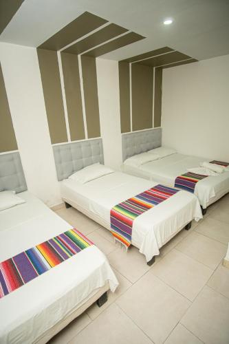 three beds in a room with white walls at Hotel Playa Divina in Coveñas