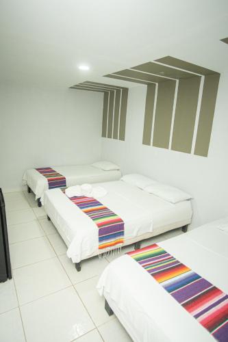 three beds in a room with white walls at Hotel Playa Divina in Coveñas