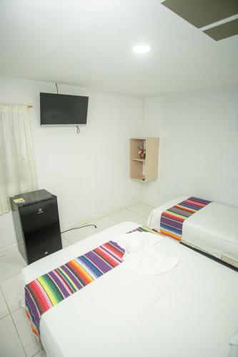 two beds in a room with a tv on the wall at Hotel Playa Divina in Coveñas