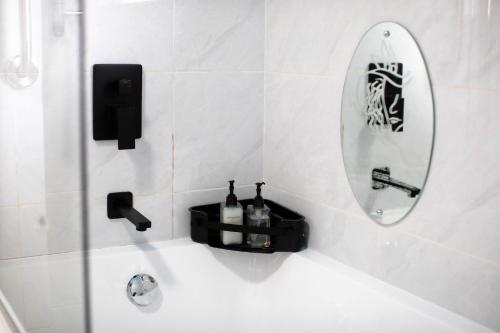 a bathroom with a tub with a mirror and bottles at Air-Conditioned, Self-Catering Apartment with Heated Pool Near OR Tambo International Airport in Benoni