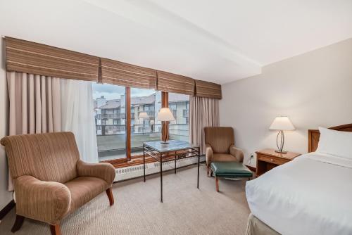 a hotel room with a bed and chairs and a window at Jasper Inn & Suites by INNhotels in Jasper