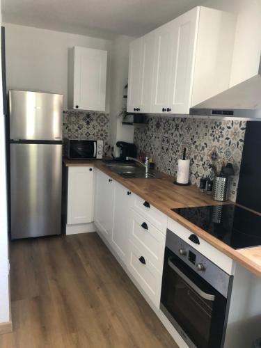 une cuisine avec des armoires blanches et un réfrigérateur en acier inoxydable dans l'établissement T2 bord de mer Plage de L'Ayguade, à Hyères