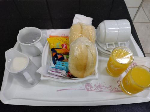 een dienblad met twee hotdogs en twee glazen sinaasappelsap bij Motel My Garden 2 in Curitiba