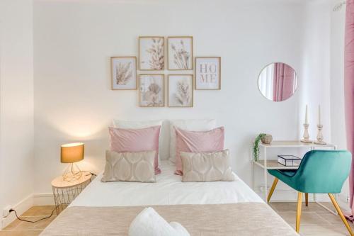 une chambre avec un lit blanc avec des oreillers roses dans l'établissement Charmant T2 proche stade de France et RER B, à Aubervilliers