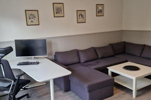 a living room with a couch and a desk with a computer at Central 2 bedroom apartment in Lillehammer