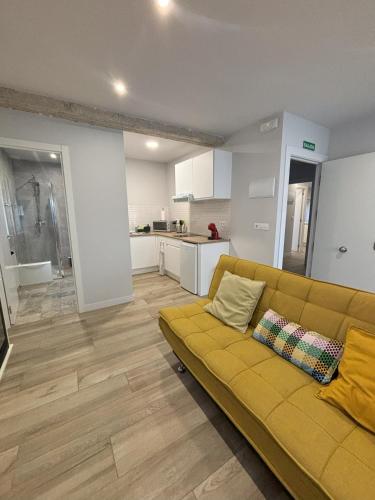 a living room with a yellow couch and a kitchen at Apartamentos Natura Cantabria in Santillana del Mar