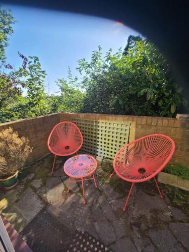 three red chairs sitting next to a fence at Stylish quiet garden flat with parking in London Zone 4 in Bromley