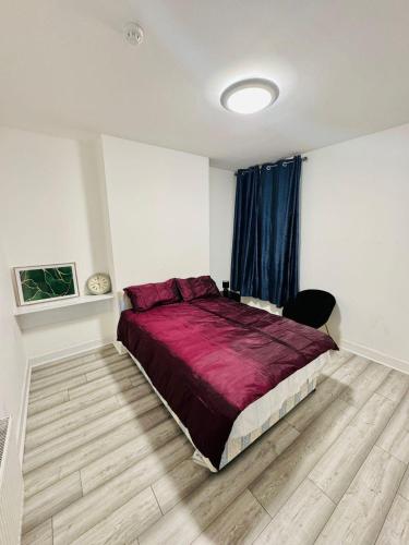 a bedroom with a large bed with a red comforter at Room for stay with shared facilities in Uxbridge