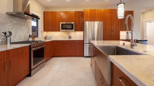 a kitchen with wooden cabinets and a stainless steel refrigerator at ALOHA SHORES Spacious Ainamalu 4BR Home with Mountain and Ocean View in Waikoloa