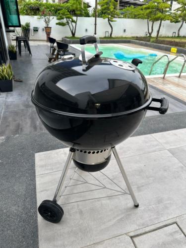 a grill sitting on a table next to a pool at Stylish villa alma in Simpang Ampat