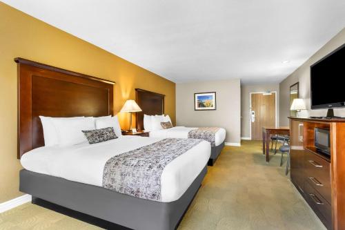 a hotel room with two beds and a flat screen tv at Best Western California City Inn & Suites in California City