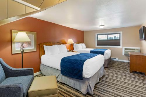 a hotel room with two beds and a couch at Best Western Sunset Inn in Cody