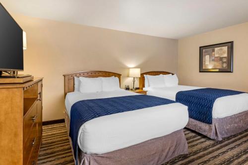 a hotel room with two beds and a flat screen tv at Best Western Sunset Inn in Cody