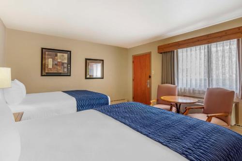 a hotel room with two beds and a table at Best Western Sunset Inn in Cody