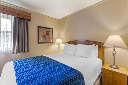 a bedroom with a large bed with a blue blanket at Best Western Sunset Inn in Cody