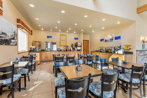 a restaurant with tables and chairs and a kitchen at Best Western Sunset Inn in Cody