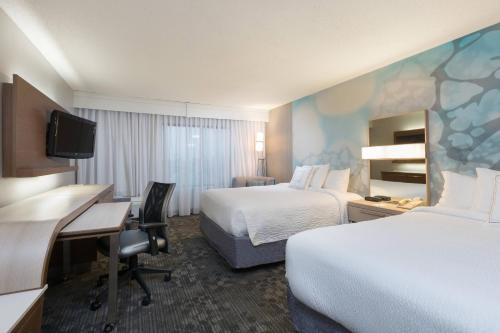 a hotel room with two beds and a desk at Courtyard Dallas Mesquite in Mesquite
