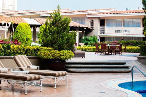 a courtyard with chairs and a table and a building at Krystal Satelite Maria Barbara in Mexico City