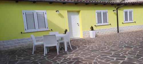 a table and chairs in front of a yellow house at Casa gialla in LʼAquila