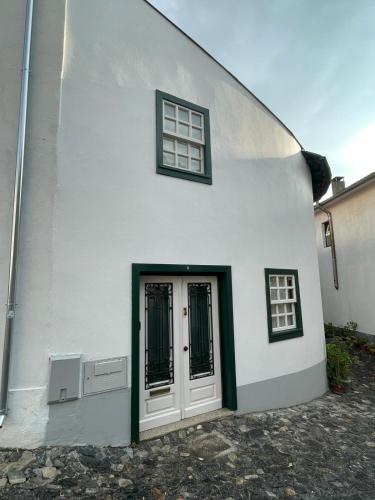 a white house with two windows and a door at Casa do Arco da Velha in Bragança