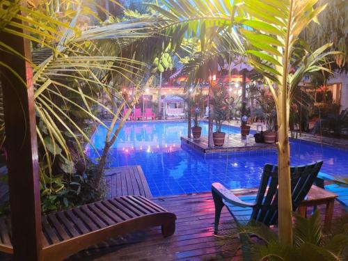 a swimming pool with a bench and palm trees at Hostal Hilltop Palomino in Palomino