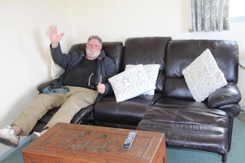 a man is sitting on a leather couch at hill view apartment in Welshpool