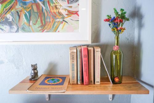 a shelf with books and a vase of flowers and a book at Laidback tradicional centric Wifi AC TV Terrace in Oaxaca City