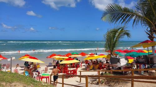 a group of people sitting under umbrellas on a beach at Dom Deco Restaurante e Pousada in Marechal Deodoro