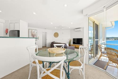 a kitchen and living room with a glass table and chairs at Spinnakers Reach Unit 9 in Batemans Bay