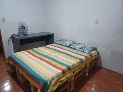 a bed with a striped comforter in a room at Mirante do Sol in São Thomé das Letras