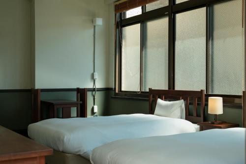 two beds in a room with two windows at Toyooka1925 in Toyooka