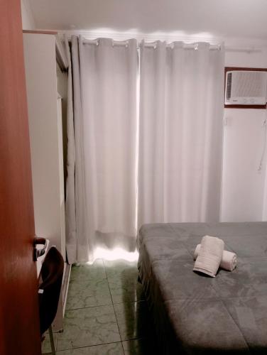a bedroom with a bed and a white curtain at Flats Via Mar in Macaé