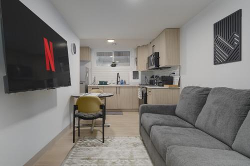 a living room with a couch and a table and a kitchen at Modern Suite by Royal Alexandra Hospital l Free Parking WiFi Netflix in Edmonton
