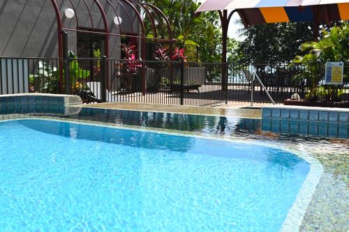 a large blue swimming pool with an umbrella at Waters Edge The Strand in Townsville