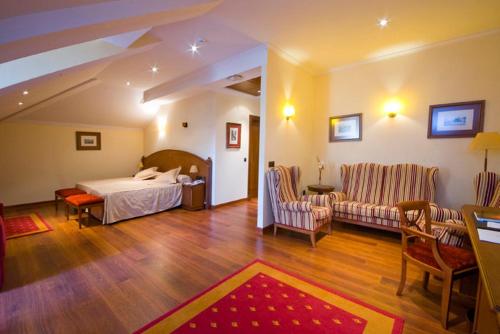 a bedroom with a bed and a living room at Hotel Palacio de la Magdalena in Soto del Barco