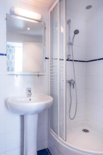 une salle de bain blanche avec un lavabo et une douche dans l'établissement Hotel des Arts - Cite Bergere, à Paris