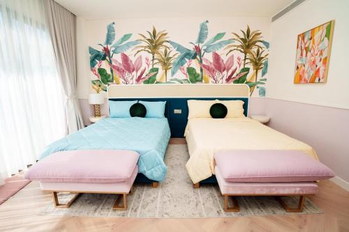 two beds in a bedroom with a mural of palm trees at Happy Stay Resort Wonderland Ho Tram in Xuyên Mộc