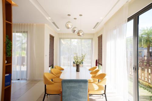 a dining room with a table and yellow chairs at Happy Stay Resort Wonderland Ho Tram in Xuyên Mộc