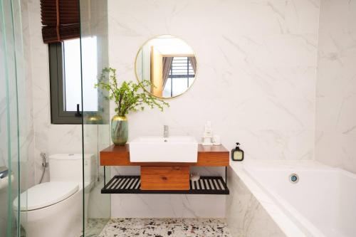 a bathroom with a sink and a tub and a mirror at Happy Stay Resort Wonderland Ho Tram in Xuyên Mộc