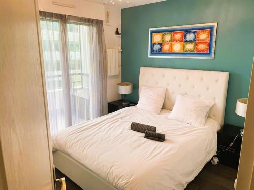 une chambre avec un lit blanc avec un mur bleu dans l'établissement LE PARADIS - 2 chambres, balcon, parking, à Boulogne-Billancourt