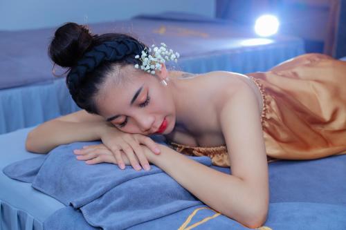a woman laying on top of a bed at Quảng Ninh Gate Hotel & Resort in Bác Mã