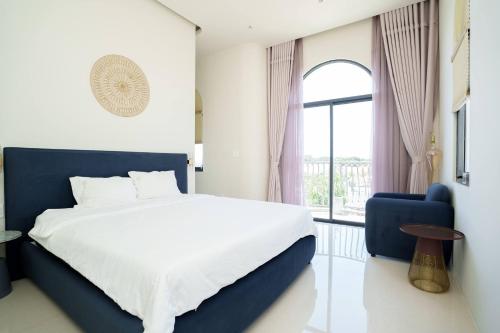 a bedroom with a large bed and a blue chair at Happy Stay Resort Wonderland Ho Tram in Xuyên Mộc