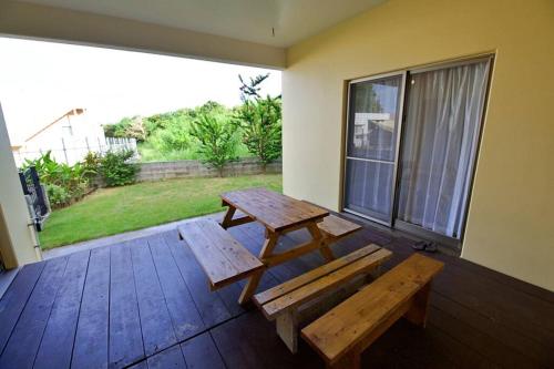 a patio with a bench and a table and a window at ラリッサ ヴィラ ウランバル in Azama