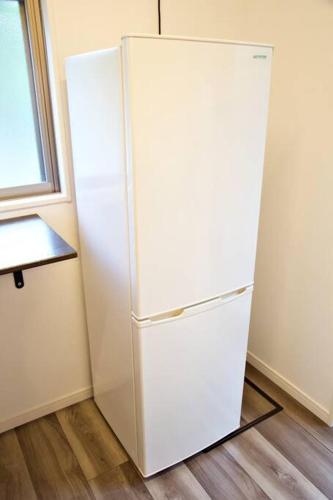 a white refrigerator in a room with a window at ラリッサ ヴィラ ウランバル in Azama