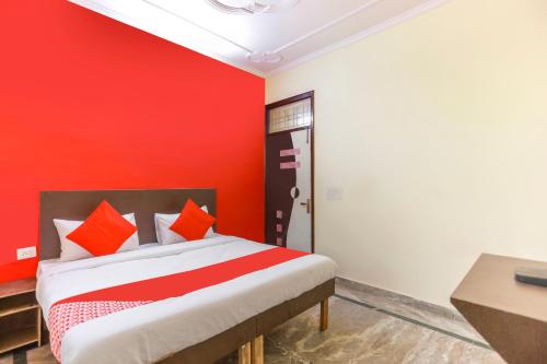 a bedroom with a red wall and a bed at Hotel O Royal Galaxy Inn in Noida