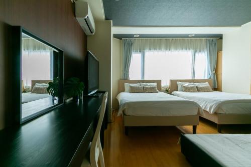 a bedroom with two beds and a tv on the wall at ELLE Namba Villa in Osaka